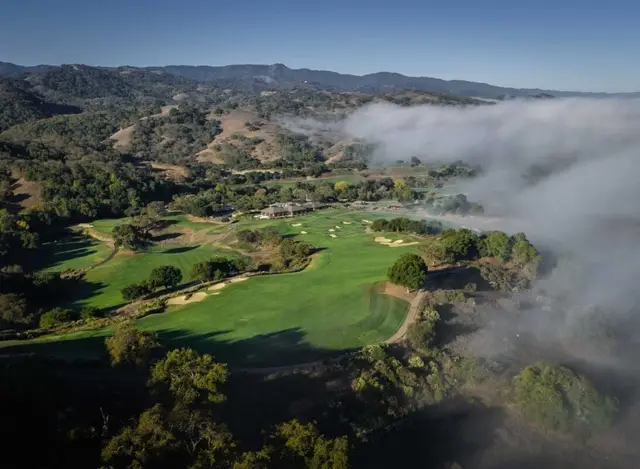 Aerial view of the course as fog rolls through the hills