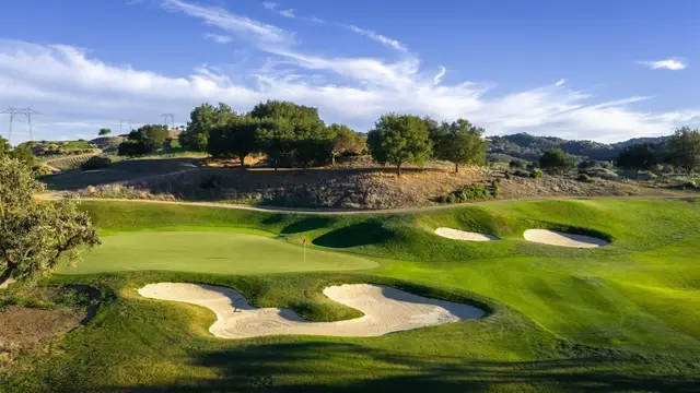 Bunkered green beneath oak-dotted hills