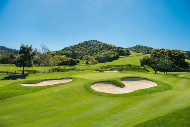 Bunkered green below oak-covered hills