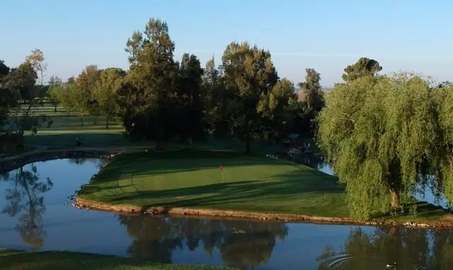 Green beside a willow-lined pond at Davis Golf Course