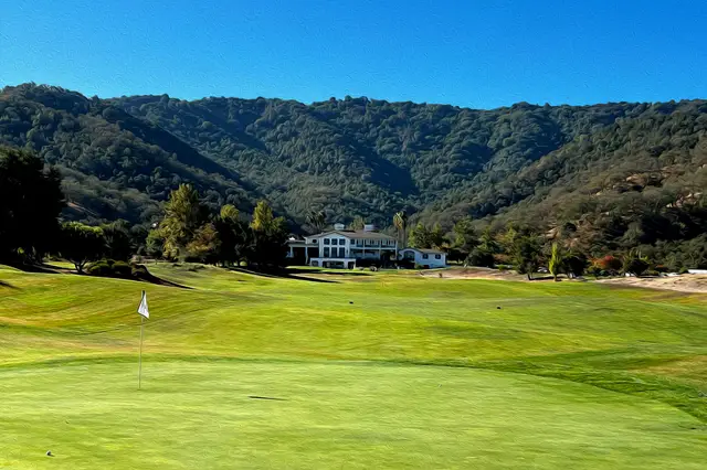 Green below the clubhouse and wooded hills at Eagle Ridge