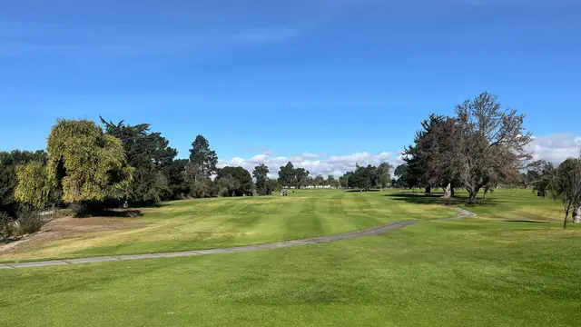 Fairway curving past oaks under a blue sky