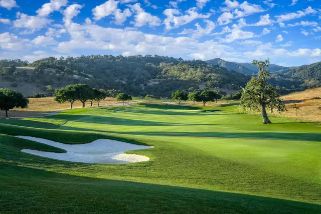 Bunkered green beneath oak-covered hills