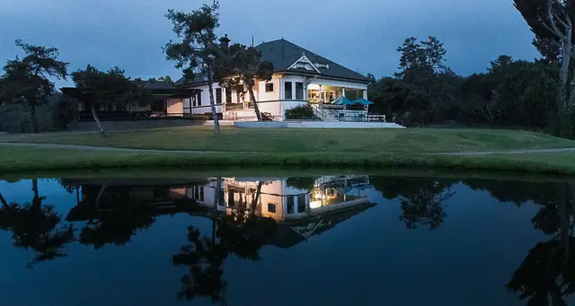 Clubhouse lit at dusk across the water