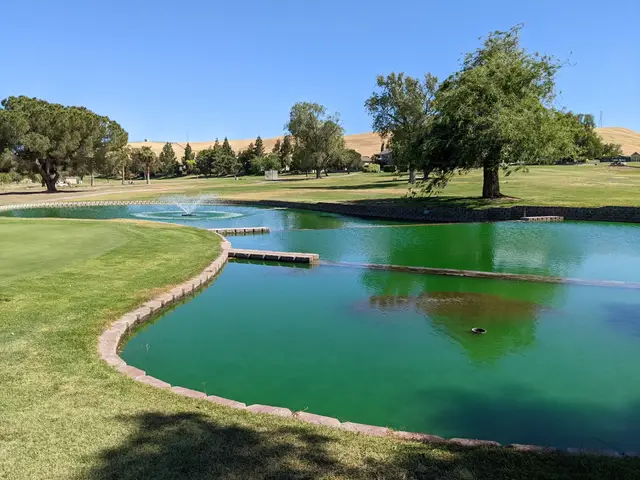Pond and fountain beside a green at Tracy