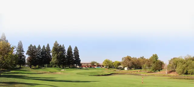 Fairway toward the clubhouse beneath tall pines at WildHawk