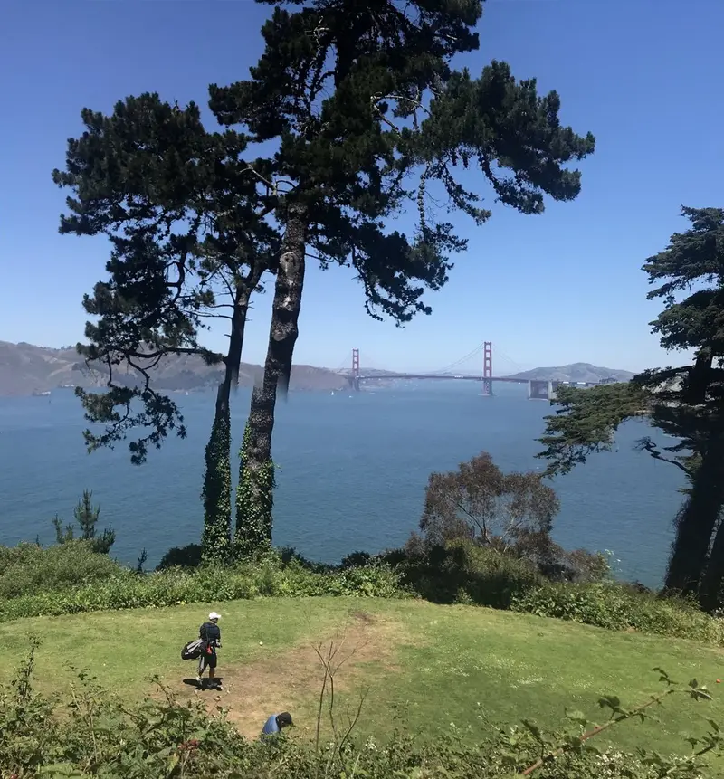 Golfers on a clifftop tee at Lincoln Park with the Golden Gate Bridge and Marin Headlands behind